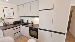 Een moderne keuken met witte kasten, een zwart aanrecht, een koffiezetapparaat en een vaatwasser.
