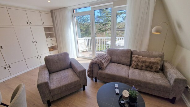 Een moderne woonkamer met een zithoek, een salontafel en uitzicht door een glazen deur op een terras.