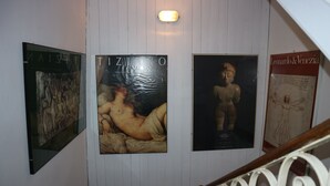 A staircase with a white railing and a wall with three framed artworks. - Venezia - Calle De Le Vele (Venice)