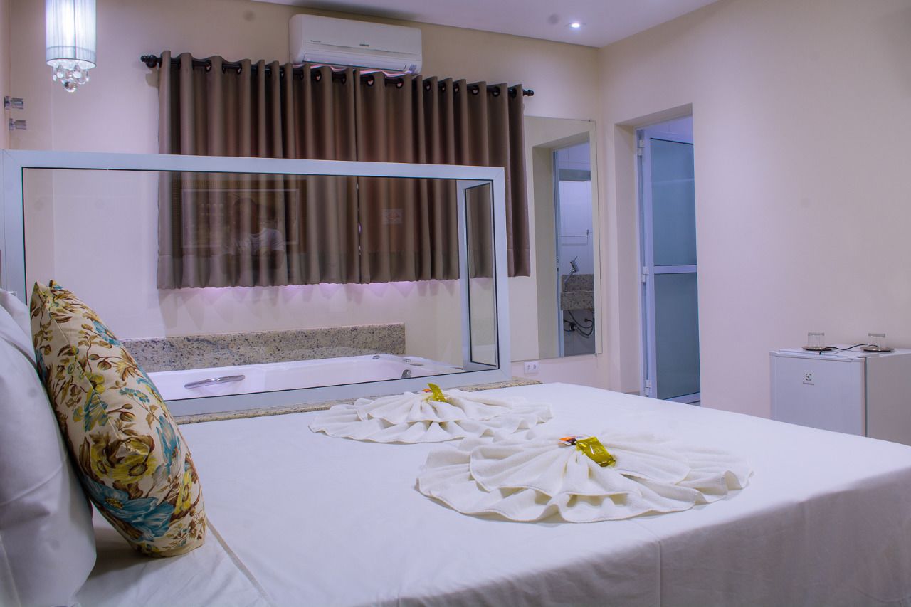 A hotel room with a large bed, a glass shower enclosure, a small bedside table, and a mirror.