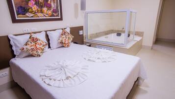 Habitación de hotel con una cama, un espejo grande, un cuadro en la pared y una mesita de noche con un teléfono y una lámpara.