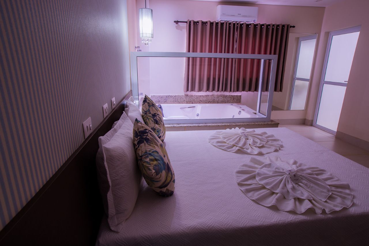 Hotellihuone, jossa on sänky, kylpyamme ja ikkuna.