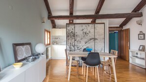 Una cocina amplia con vigas de madera, un comedor con mesa y sillas, y vistas al salón contiguo.