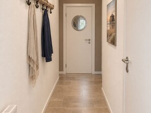 Un couloir avec une porte blanche, un porte-serviettes avec des serviettes et un tableau encadré au mur.