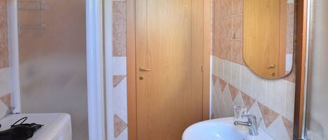 A bathroom with a washing machine, a sink, and a wooden door.