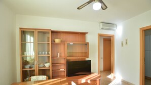 Una sala de estar con un aparador de madera, un televisor de pantalla plana y una mesa de comedor con un plato.