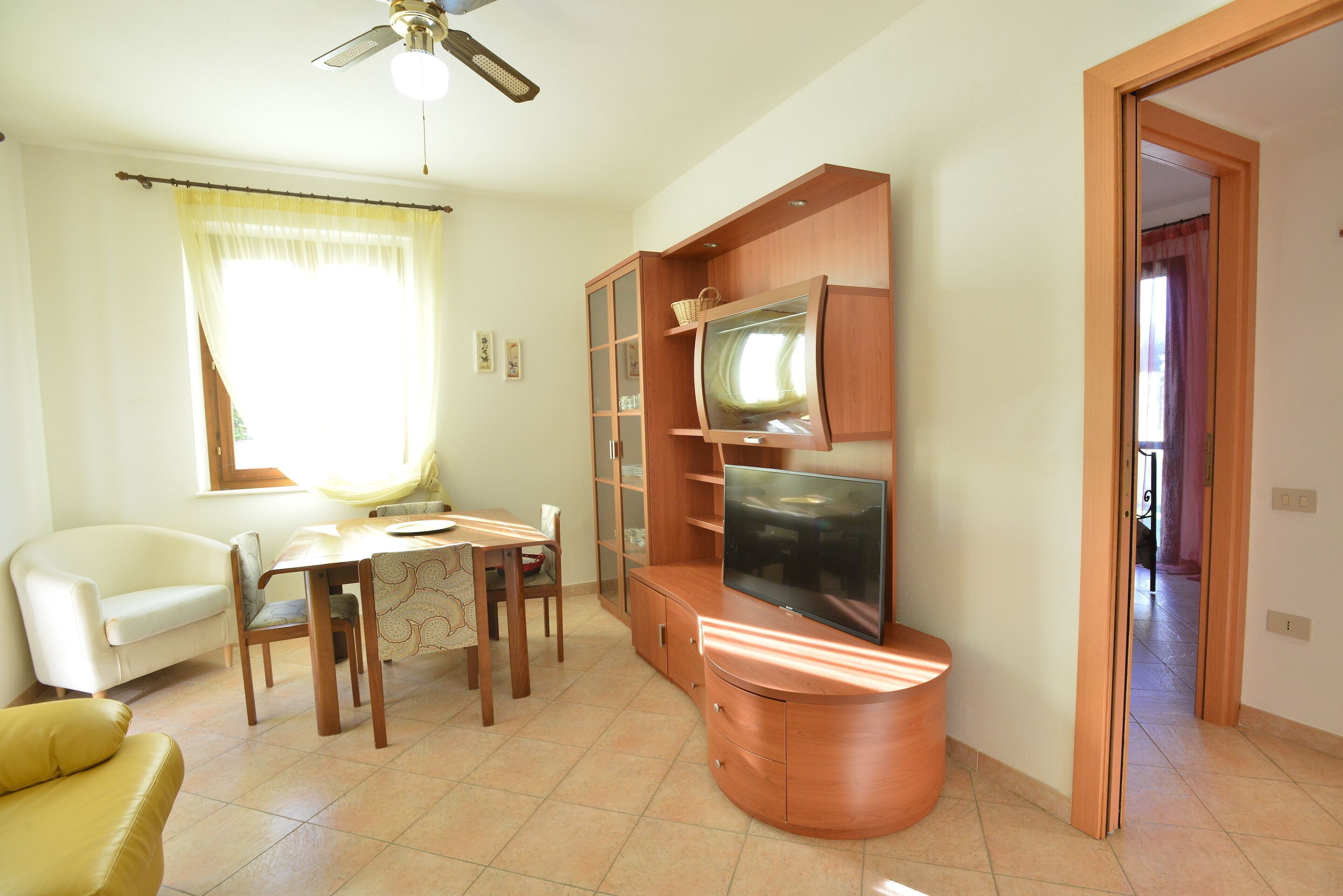 Una sala de estar con televisor, mueble de madera y un comedor con mesa y sillas.