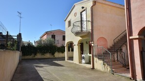 Un estrecho callejón con un edificio que tiene un balcón y una lavadora afuera.