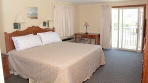 A hotel room with a large bed, a desk, two lamps, and a view of the outdoors through a sliding glass door. - Perfect For Wedding Guest, Friends Getaway Or Family Vacation (Middletown)