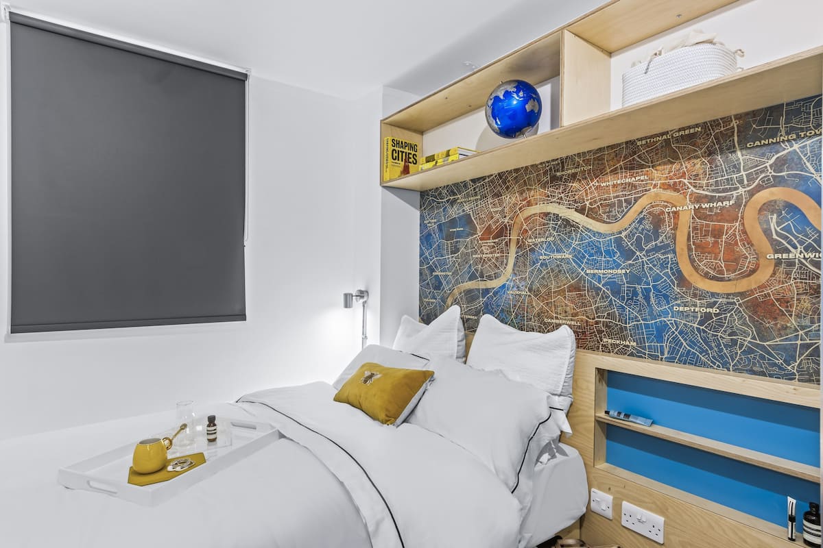 A neatly arranged bedroom with a bed, a tray with toiletries, a map on the wall, and a globe on a shelf.