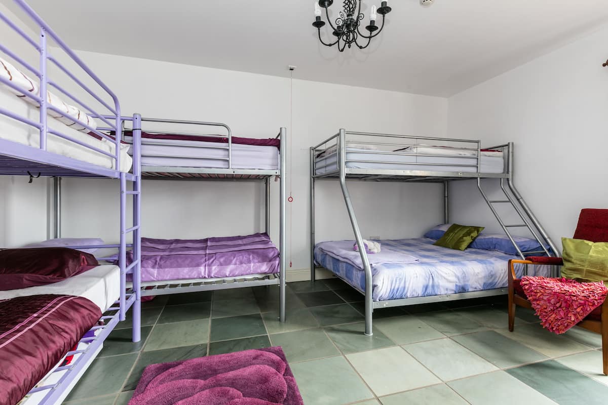 A dormitory room with bunk beds, a chandelier, and a chair with a blanket.