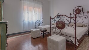 A bedroom with a four-poster bed, a small bedside table, and a chair. - Lido Venezia - Via Smirne 9 (Venice)