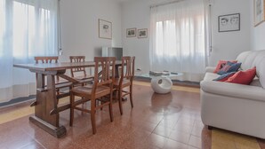 A living room with a dining table, chairs, a sofa, and a TV. - Lido Venezia - Via Smirne 9 (Venice)