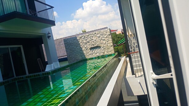 A swimming pool with green tiles, a stone wall, and a metal railing. - 3BRs 5 BathRms with private pool in BKK, 3 km to metro ,9 km to BKK airport (Bangkok)