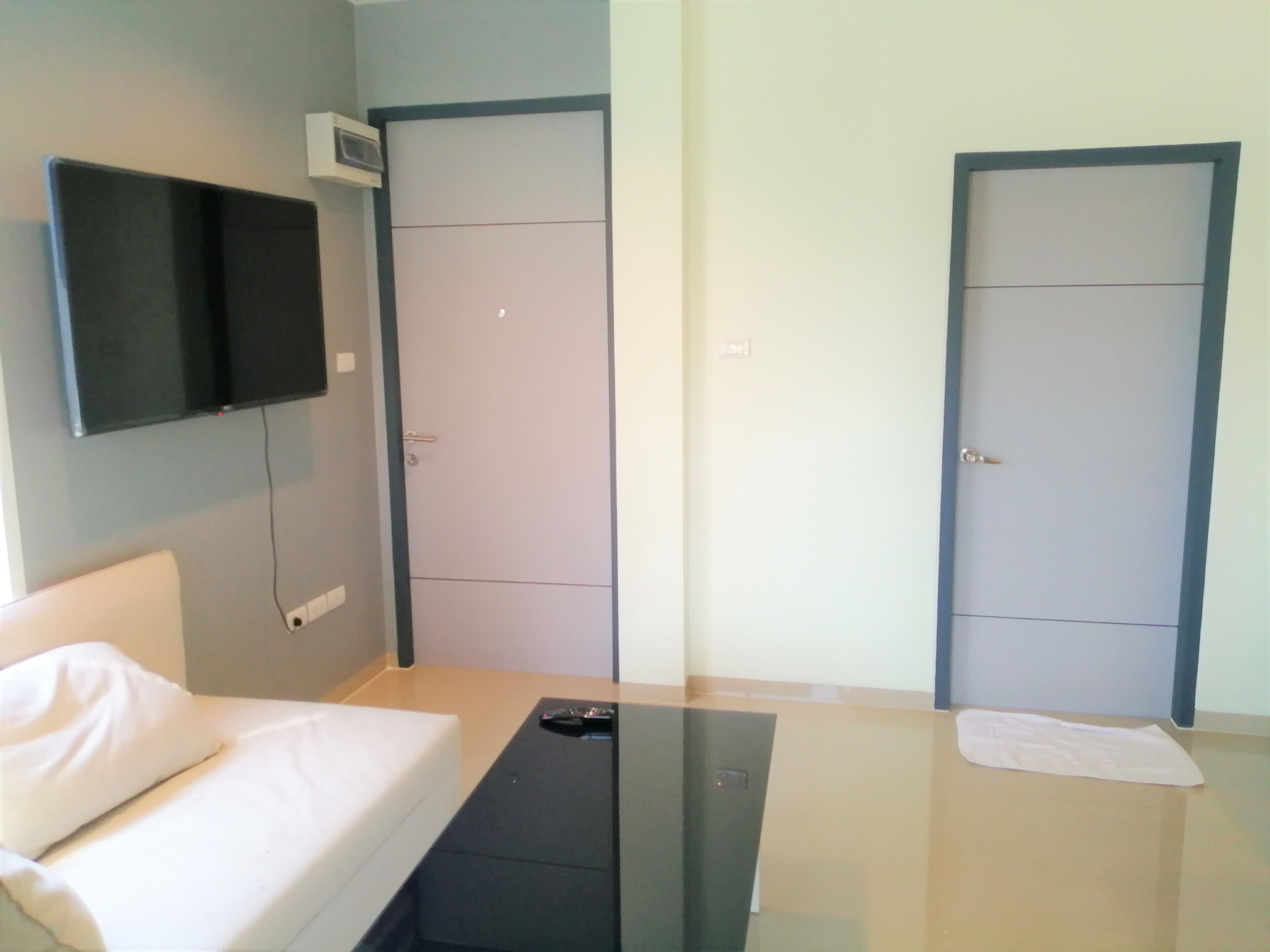 Une chambre d’hôtel moderne équipée d’un lit, d’un téléviseur à écran plat fixé au mur et de deux portes.