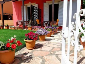 A courtyard with potted flowers and outdoor furniture. - Irini SeaSide Studios (Lefkada)