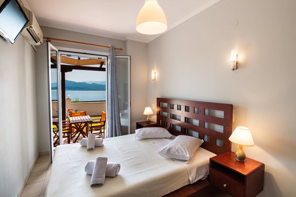 Habitación de hotel con cama, lámparas de noche, televisión y vistas al exterior.