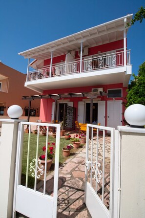 A two-story building with a balcony, potted plants, and a gated entrance. - Irini SeaSide Studios (Lefkada)