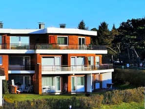 Uma casa moderna de dois andares, com janelas amplas, varanda e um jardim bem cuidado.