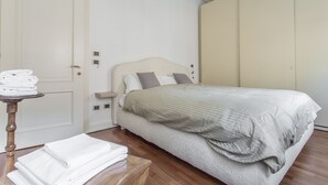 A bedroom with a bed, a bedside table with towels, a door, and a wardrobe. - Venezia - San Pantalon 3700 (Venice)