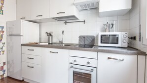 A modern kitchen with white cabinets, a built-in oven, a microwave, and a stainless steel sink. - Venezia - San Pantalon 3700 (Venice)