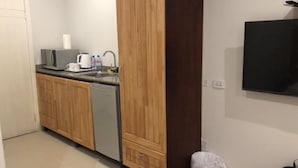 Une cuisine de taille réduite, dotée de meubles en bois, d’un lave-vaisselle, d’une machine à café et d’un évier.