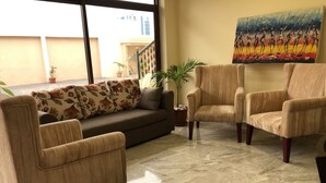 Un salon comprenant un canapé, deux fauteuils, une table basse et un tableau accroché au mur.