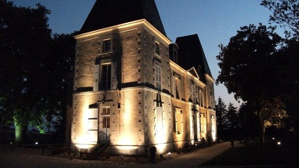 A large, historic stone building with multiple windows and a prominent tower, illuminated at night. - Château de Belle-Vue (Sainte-Cecile)