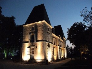 A large, historic stone building with multiple windows and a prominent tower, illuminated at night. - Château de Belle-Vue (Sainte-Cecile)