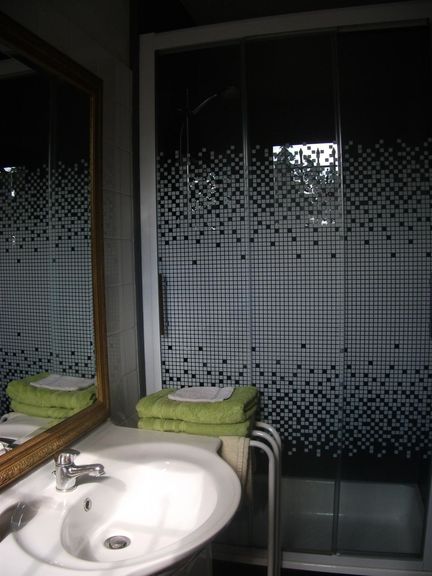 Ein Badezimmer mit Waschbecken, Spiegel und einem Fenster mit einer Wand aus gemusterten Fliesen.
