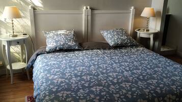 A neatly made bed with a floral-patterned bedspread, two matching pillows, and two bedside tables with lamps.