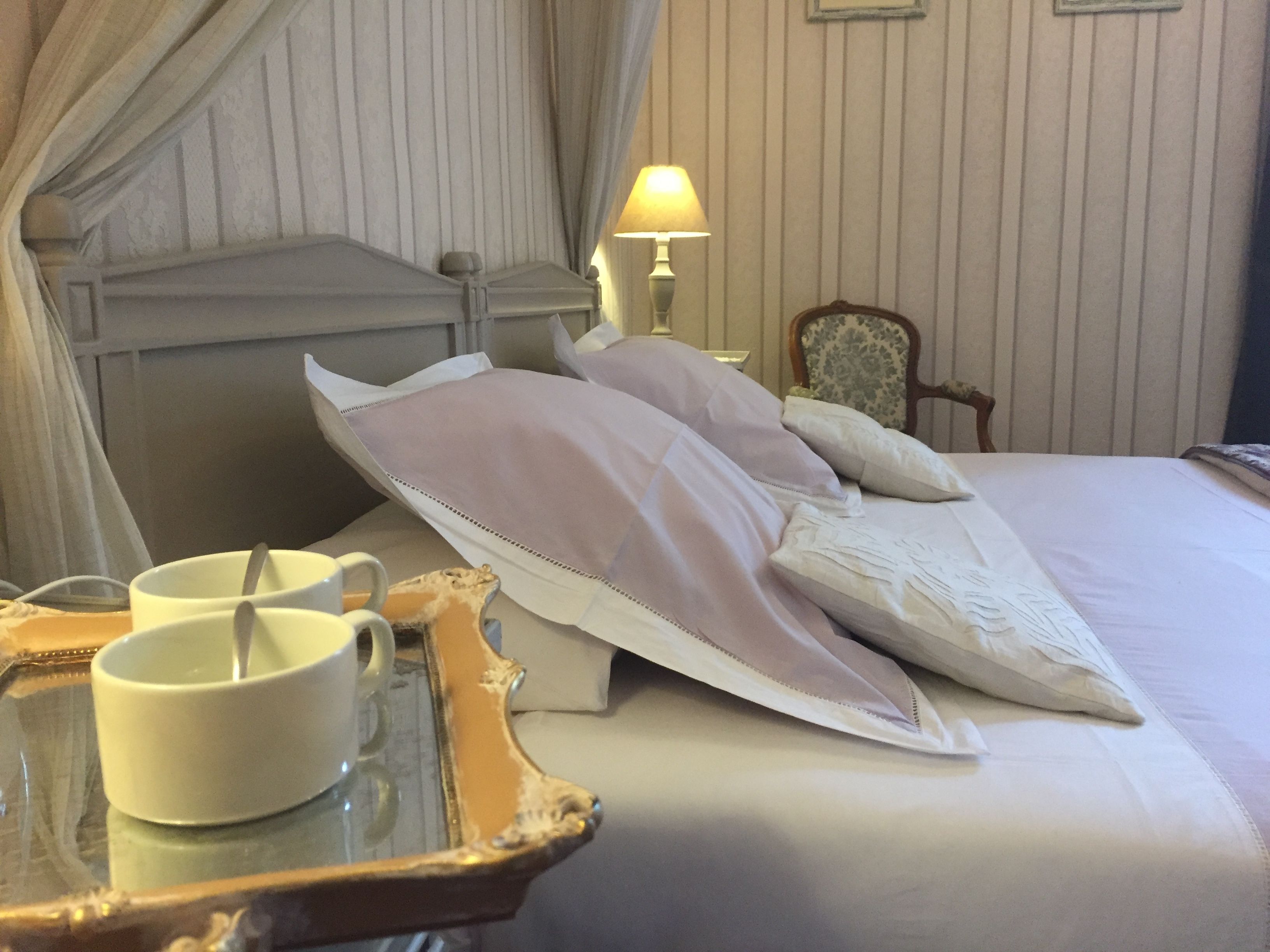 Une chambre d’hôtel avec un lit, une table de chevet avec un plateau, une lampe et une chaise.