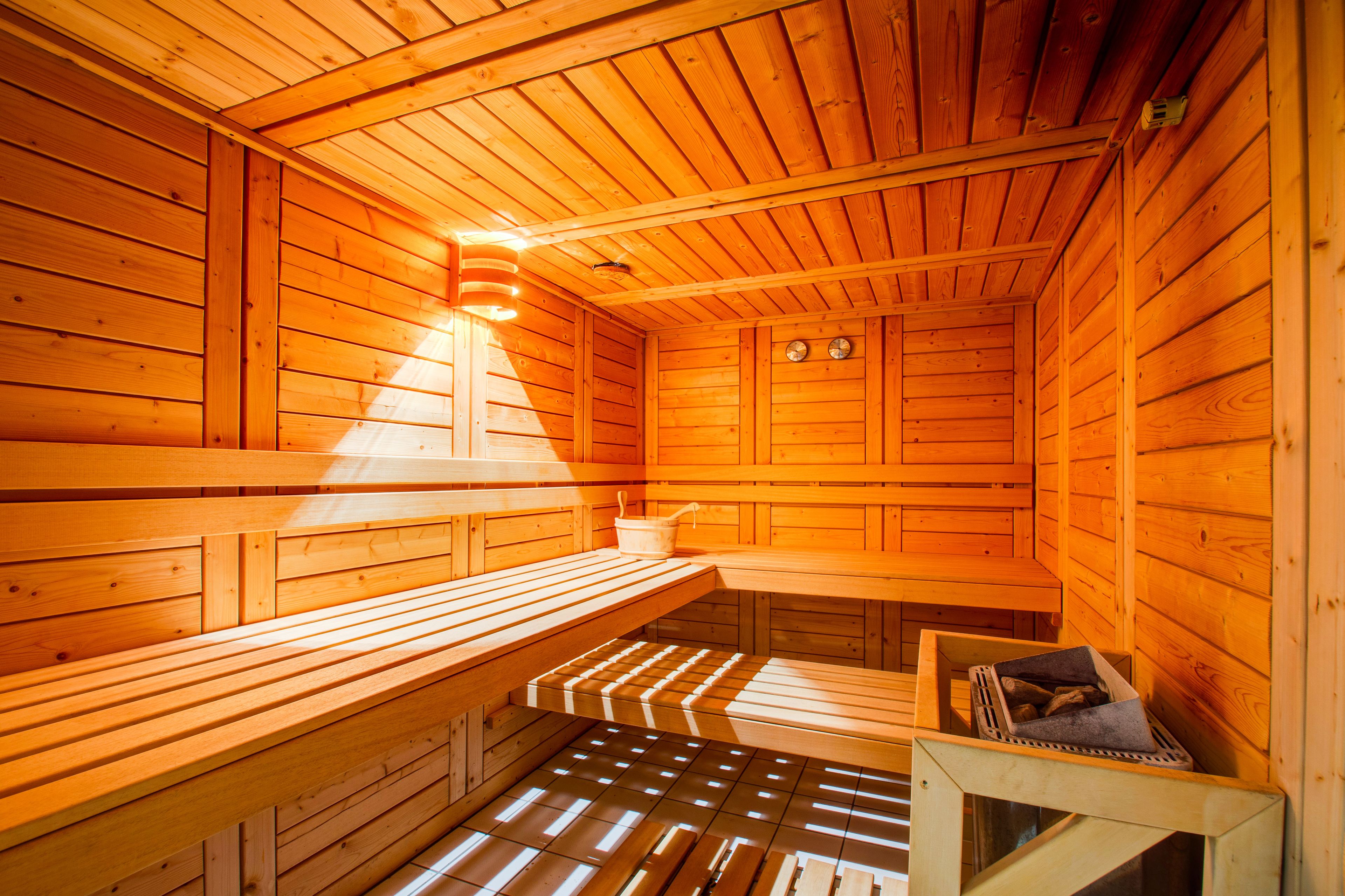 Un sauna avec des bancs en bois et un banc muni d’une serviette.