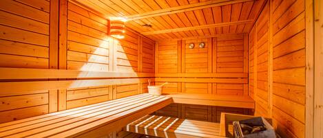 Una sauna con bancos de madera y un banco con toalla.