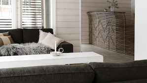 A modern living room with a dark grey sofa, a white coffee table, and a decorative candle. - Wooddream (Taipalsaari)
