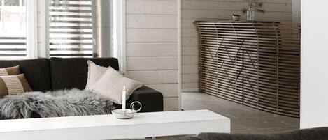 A modern living room with a dark grey sofa, a white coffee table, and a decorative candle.