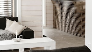 A modern living room with a dark sofa, white coffee table, and a decorative wall panel. - Wooddream (Taipalsaari)