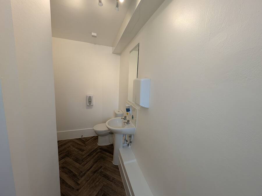 Et badeværelse med toilet, håndvask og spejl.