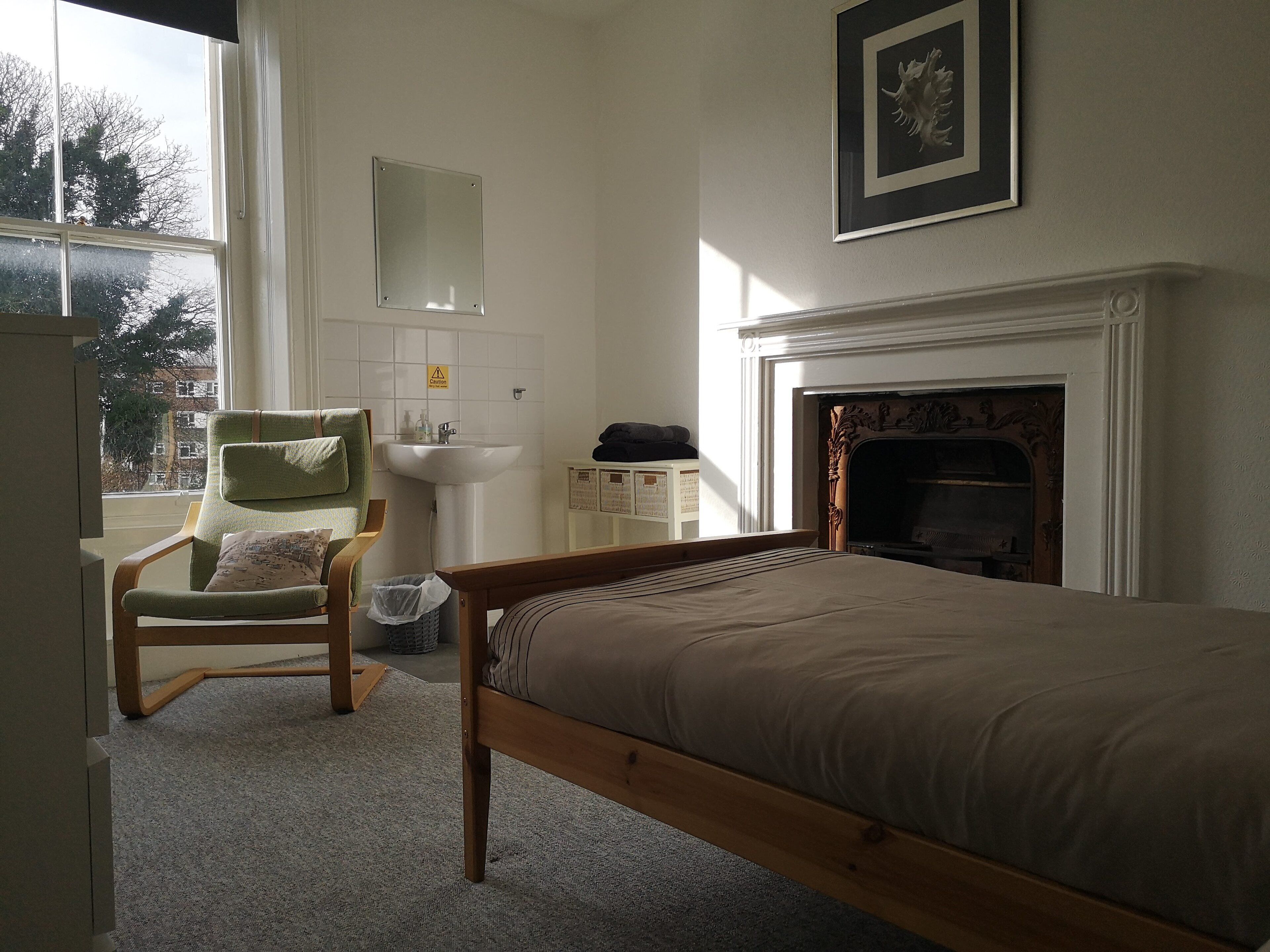 Un dormitorio con cama, una silla, un lavamanos y una chimenea.