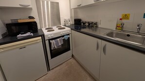 A compact kitchen with a microwave, stove, oven, and sink. - Dover Town Rooms (Dover)