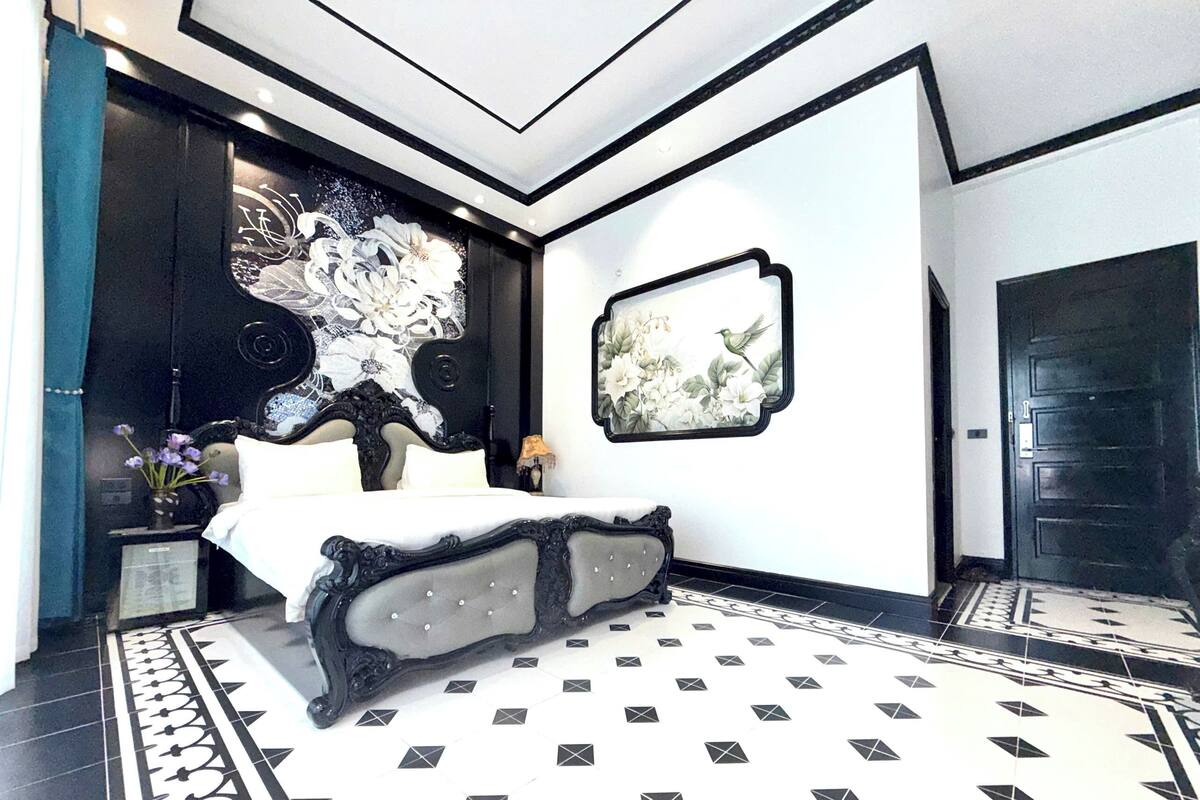 Une chambre moderne avec un grand lit, un mur décoratif et une porte noire.