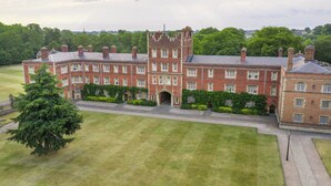 A large, historic building with multiple wings and a central tower, surrounded by well-maintained lawns and trees. - West Court - Cambridge - Campus Accommodation (Cambridge)