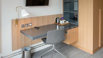 A modern office space with a desk, chair, and a mounted TV.