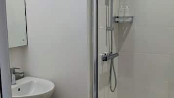 A modern bathroom with a glass-enclosed shower, a white sink, and a toilet.