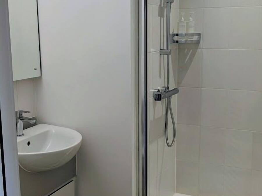 A modern bathroom with a glass-enclosed shower, a white sink, and a toilet.