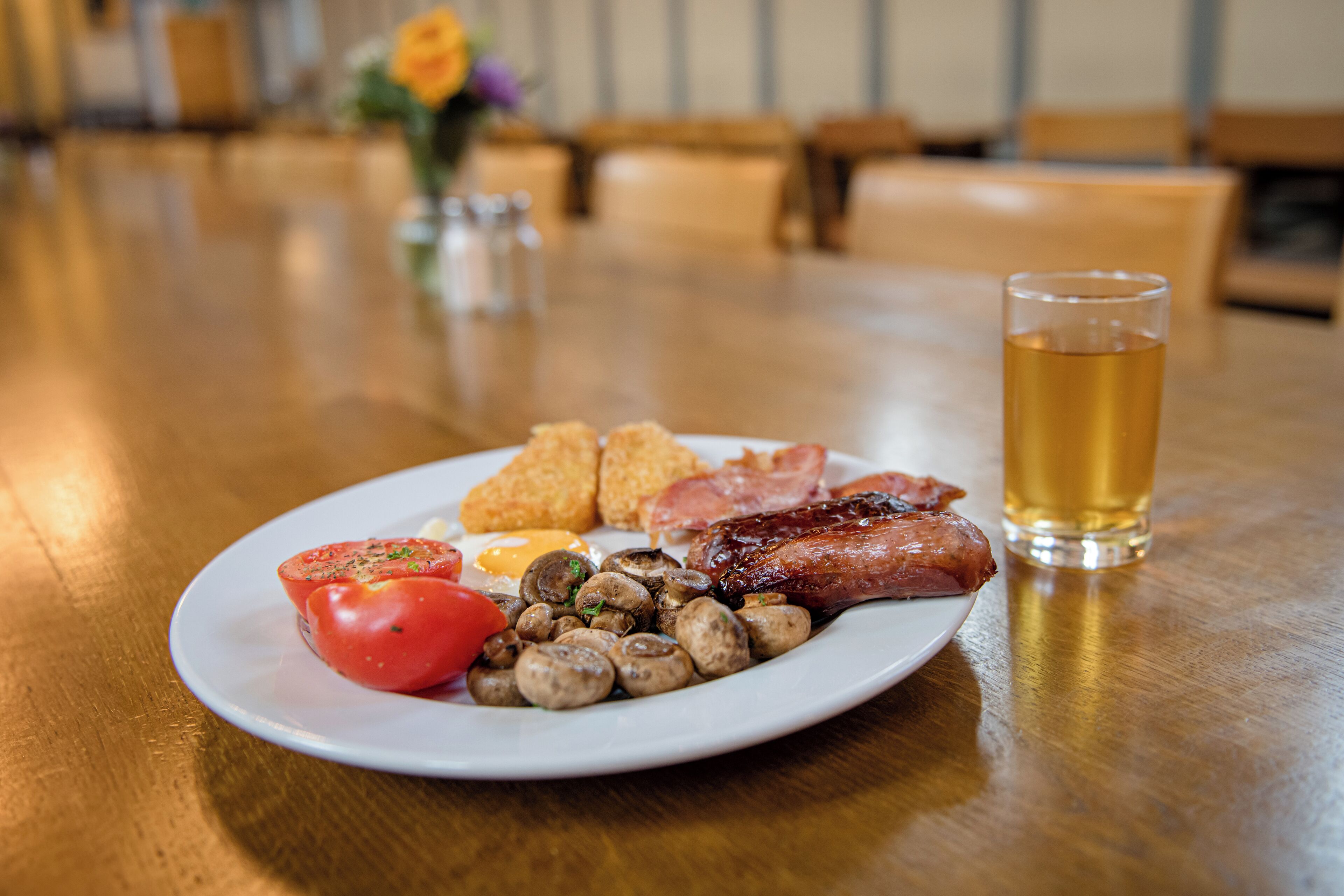 A plate of food with a glass of beer on a wooden table.