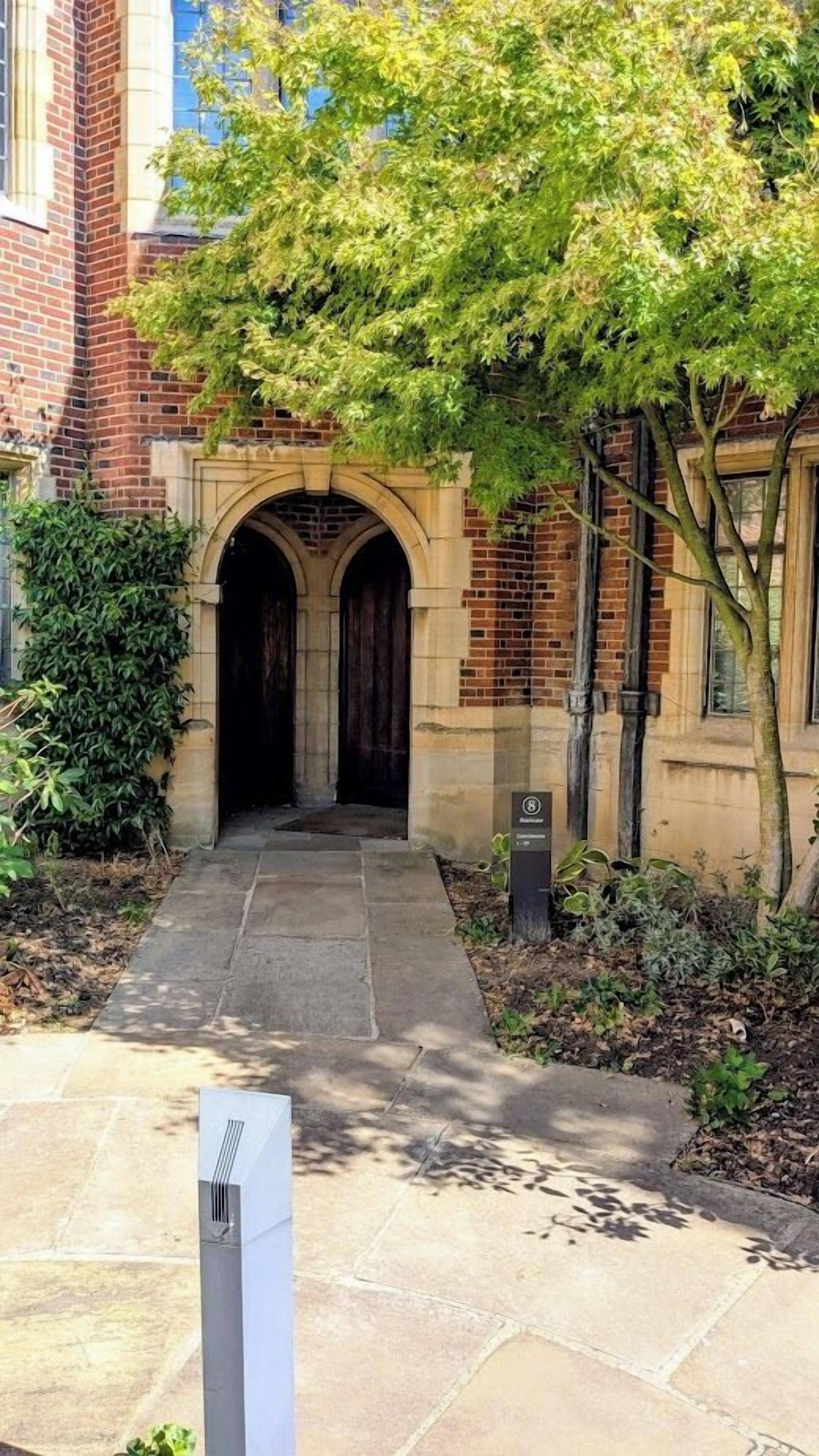 A building entrance with a brick facade, an arched doorway, and a pathway leading to the entrance.