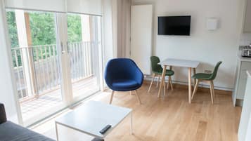 A modern living room with a balcony, a dining area, and a TV mounted on the wall.