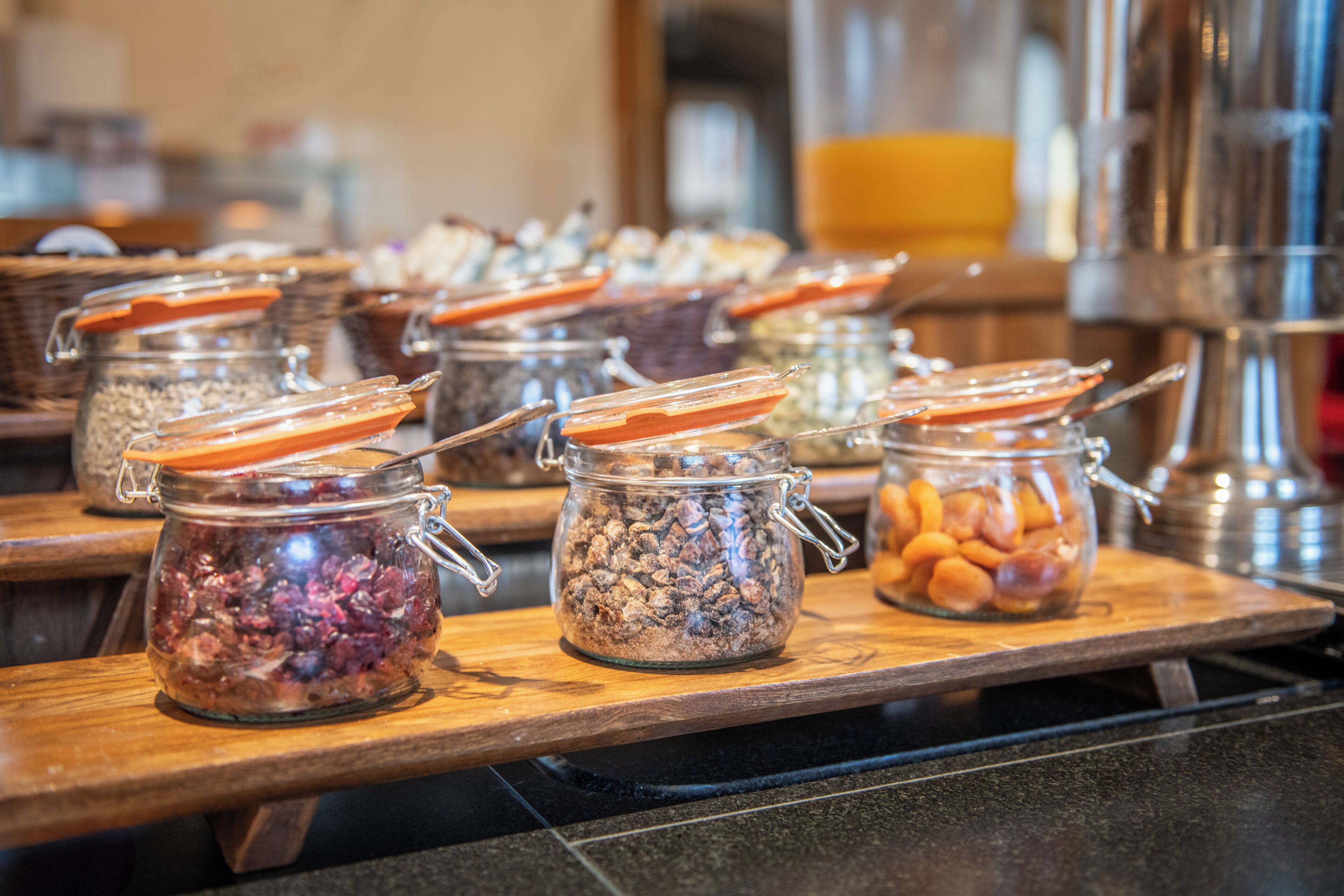 A buffet with various food items in glass containers on wooden serving boards.
