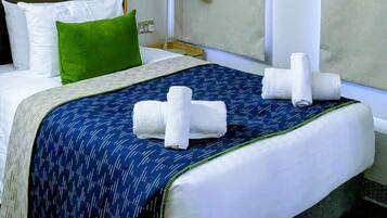 Une chambre d’hôtel avec un lit, une table de chevet, une lampe et un tableau encadré au mur.